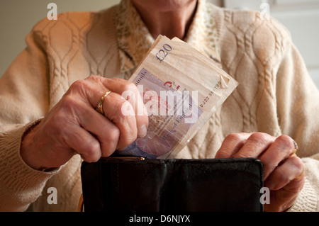 Femme âgée femme âgée de 20 livres mettant en sac à main Banque D'Images