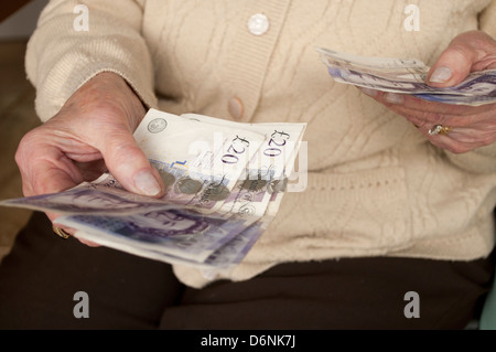 Personnes âgées caucasian woman holding out notes de 20 livres Banque D'Images