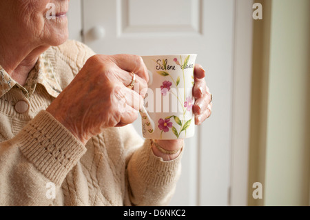 Personnes âgées femme boit un thé tout en regardant par la fenêtre Banque D'Images