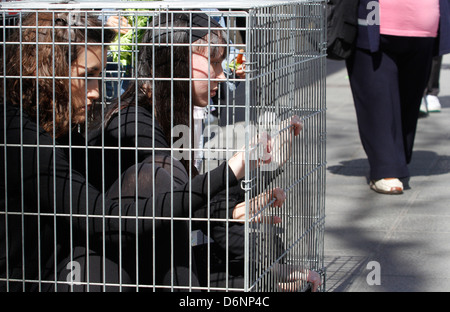 Ci-joint les militants dans une cage observés au cours d'une performance de rue Banque D'Images