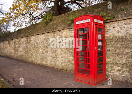 Un classique de la cabine téléphonique rouge contre un mur de pierre à Oxford. Banque D'Images