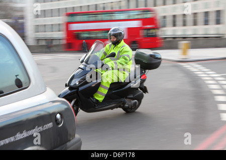 Un motocycliste et une partie de la course en taxi de la saisie d'un rond-point à Londres, en Angleterre. Banque D'Images