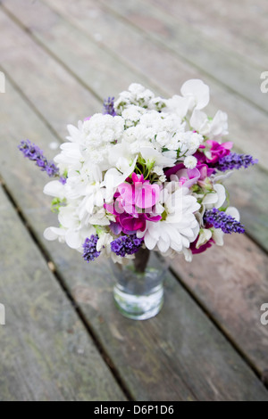 Blanc et violet , rose bouquet de fleurs arrangées de façon informelle dans un bocal en verre sur la terrasse en bois Banque D'Images