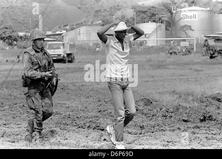 Un Marine armé d'un M16A1 rifle escorte un capturé membre de l'Armée révolutionnaire des peuples au cours de l'opération URGENT FURY. Banque D'Images