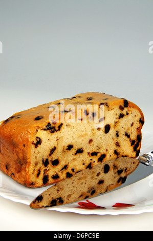 Sultana gâteau aux fruits sur une plaque blanche avec un couteau à gâteau. Banque D'Images