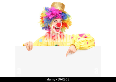 Un heureux homme clown pointant sur un panneau vide isolé sur fond blanc Banque D'Images