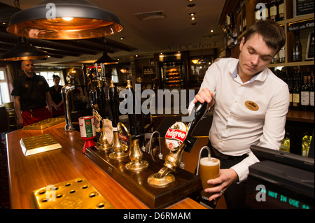 Un barman pulling a pint de bière pression, de vraie bière dans un pub UK Banque D'Images