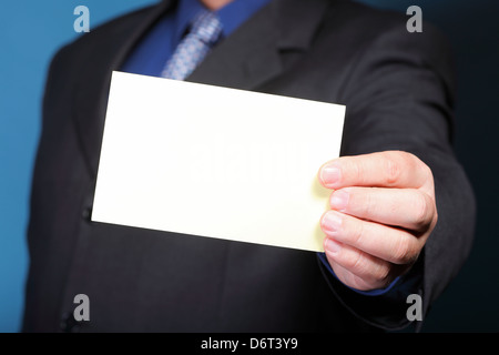 Gros plan du blank business note card ou pancarte dans la main de l'homme fond bleu Banque D'Images