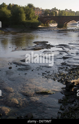 Pont de pierre en arc sur la rivière avec l'eau peu profonde sur des pierres et rochers en premier plan Banque D'Images