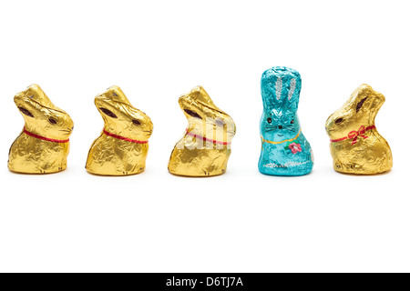 Chocolat or jaune quatre lapins de Pâques à la recherche d'un lapin de Pâques bleu pour illustrer de se démarquer de la foule et concept de leadership Banque D'Images