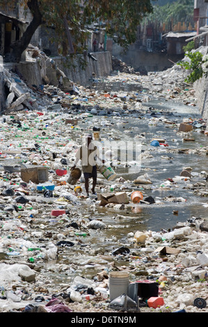 L'homme à une poubelle rempli Rivière, Port au Prince, Haïti, Caraïbes Banque D'Images