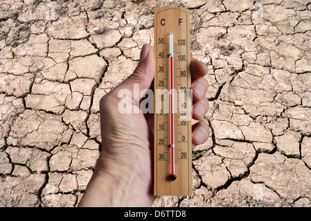 Main tenant un thermomètre indiquant le changement climatique en raison de l'augmentation des températures mondiales. Banque D'Images