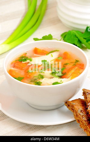 Soupe au poulet avec des légumes dans un bol blanc sur une table Banque D'Images