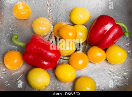 Le lavage des fruits et légumes dans l'évier de la cuisine. Banque D'Images