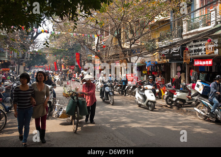 Cityscape horizontale typique d'une rue animée dans le vieux quartier de Hanoi avec les mobylettes et les gens le partage de la route sur une journée ensoleillée Banque D'Images