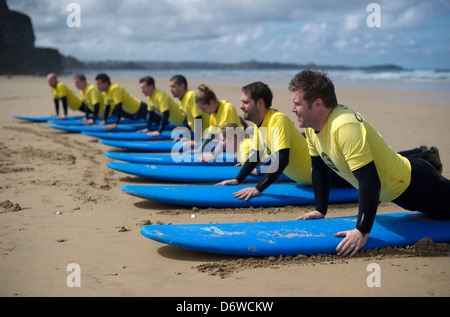 Les étudiants au cours d'une leçon de surf sur la plage à Watergate Bay, Cornwall, UK Banque D'Images