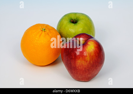 Deux pommes et une orange sur un fond uni. Banque D'Images