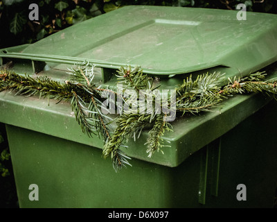 Arbre de Noël dans un jardin vert à kirbside poubelle à roulettes Banque D'Images