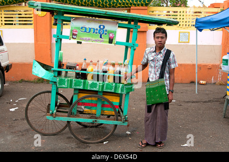 Homme birman se trouve à côté de son panier vendant des boissons sur une rue de Yangon Myanmar Birmanie Banque D'Images