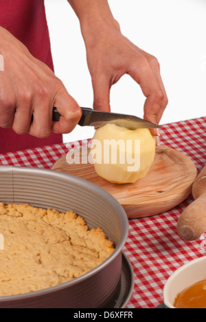 Gâteau aux pommes en devenir, femme mains couper une pomme épluchée Banque D'Images