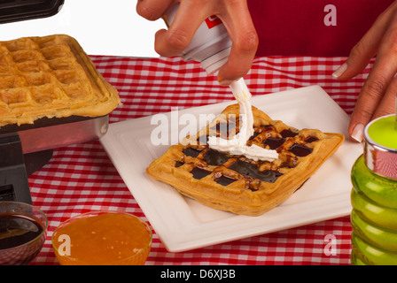 Femmes décorant des gaufres avec une sauce au chocolat et crème Banque D'Images