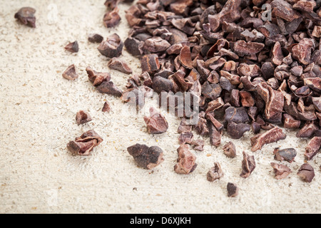 Close-up d'un tas de matières premières cacao nibs sur un fond de bois grange peint en blanc Banque D'Images