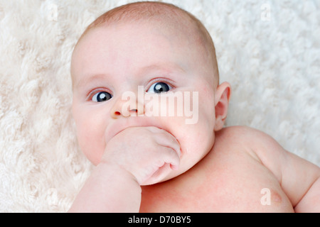 Portrait de beau bébé de 3 mois et de succion sur sa main pour soulager lui-même Banque D'Images