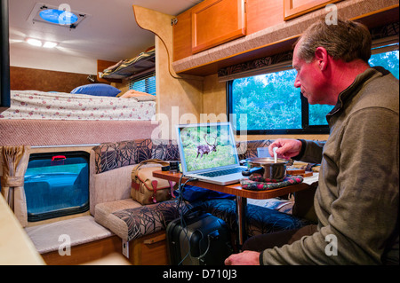 L'édition de photographe professionnel photos numériques sur un ordinateur portable à l'intérieur d'un camping-camion, Denali National Park, Alaska USA Banque D'Images