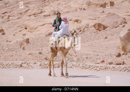 Deux jeunes équitation bédouin sur un chameau, le chameau d'Arabie (Camelus dromedarius), péninsule du Sinaï, Égypte Banque D'Images
