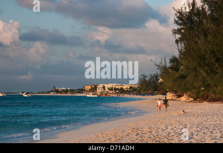 Couple en train de marcher le long de Grace Bay à Providenciales, Turks et Caicos au coucher du soleil Banque D'Images