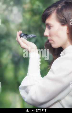 Une femme dans une robe vintage avec le crâne d'un corbeau dans sa main Banque D'Images