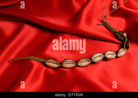 Collier de coquillages sur fond de satin rouge. Banque D'Images