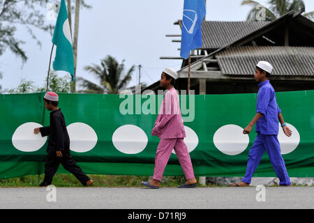 Dungun, Terengganu, Malaisie. Le 26 avril 2013. Les garçons musulmans à pied passé parti de l'opposition malaisienne, Parti islamique malais (PAS) banner de Dungun, à quelque 300 kilomètres au nord-est de Kuala Lumpur. La Malaisie se rendront aux urnes le 5 mai. 222 Total 505 sièges parlementaires et l'état seront contestées. (Crédit : Crédit : Image Najjua ZUMAPRESS.com/Alamy Zulkefli/Live News) Banque D'Images