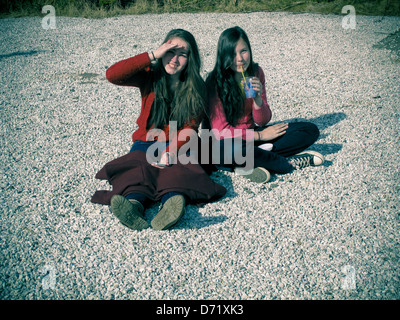 Deux soeurs assis sur le gravier en soleil Banque D'Images