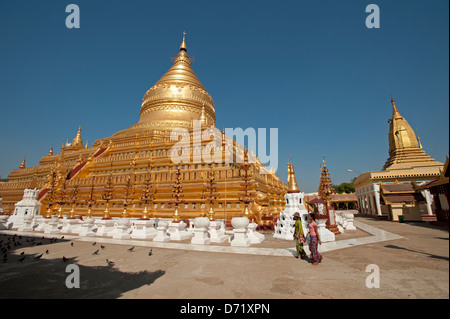 Deux femmes birmanes passent devant le grand dôme d'or de la Pagode Shwezigon Bagan Myanmar (Birmanie) Banque D'Images