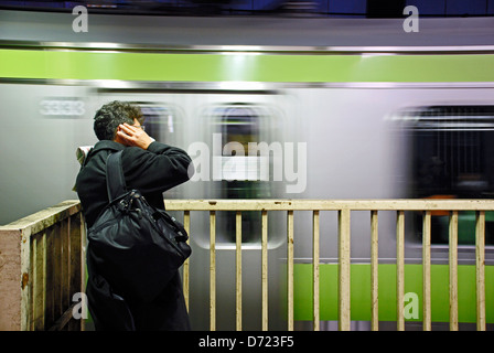 Un homme attend son train à la station de métro à Tokyo, Japon. Banque D'Images