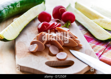 Couper les radis courgettes et saucisses on cutting board Banque D'Images