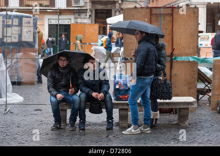 Les gens à l'abri de la pluie sous des parasols sur la Piazza Navona, Rome, Italie Banque D'Images