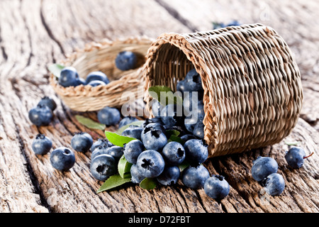 Les bleuets ont chuté à partir du panier sur une vieille table en bois. Banque D'Images