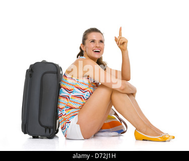 Jeune femme avec sac roue tourisme assis sur le plancher et en pointant sur l'espace de copie Banque D'Images