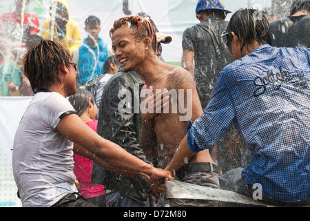 Les jeunes hommes grimpent sur les véhicules en mouvement à la danse et se font avoir comme ils passent par les plates-formes de l'eau au cours de la célébration. Thingyan Banque D'Images