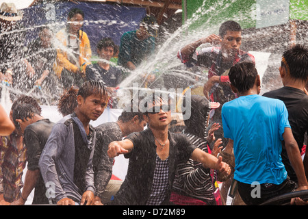 Les jeunes hommes grimpent sur les véhicules en mouvement à la danse et se font avoir comme ils passent par les plates-formes de l'eau au cours de la célébration. Thingyan Banque D'Images