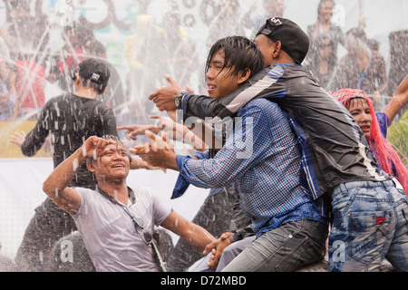 Les jeunes hommes grimpent sur les véhicules en mouvement à la danse et se font avoir par les nombreux cours d'eau au cours de la fête de l'eau Thingyan. Banque D'Images