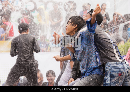 Les jeunes hommes grimpent sur les véhicules en mouvement à la danse et se font avoir par les nombreux cours d'eau au cours de la fête de l'eau Thingyan. Banque D'Images