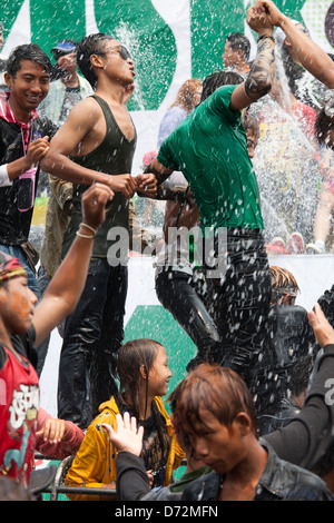 Les jeunes hommes grimpent sur les véhicules en mouvement à la danse et se font avoir par les nombreux cours d'eau au cours de la fête de l'eau Thingyan. Banque D'Images