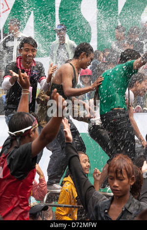 Les jeunes hommes grimpent sur les véhicules en mouvement à la danse et se font avoir par les nombreux cours d'eau au cours de la fête de l'eau Thingyan. Banque D'Images