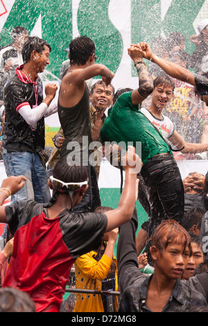 Les jeunes hommes grimpent sur les véhicules en mouvement à la danse et se font avoir par les nombreux cours d'eau au cours de la fête de l'eau Thingyan. Banque D'Images