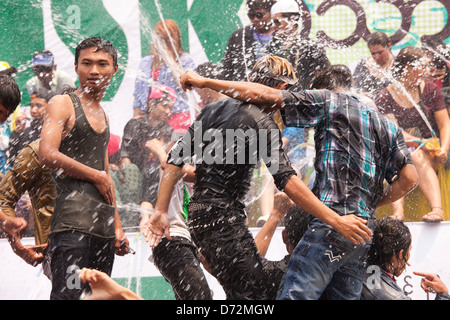 Les jeunes hommes grimpent sur les véhicules en mouvement à la danse et se font avoir par les nombreux cours d'eau au cours de la fête de l'eau Thingyan. Banque D'Images