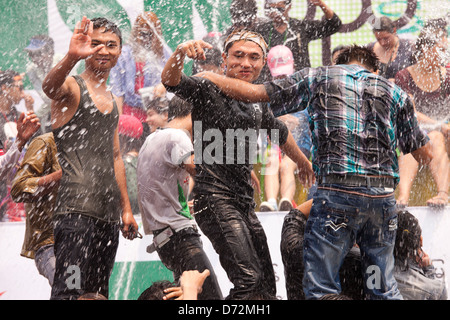 Les jeunes hommes grimpent sur les véhicules en mouvement à la danse et se font avoir par les nombreux cours d'eau au cours de la fête de l'eau Thingyan. Banque D'Images