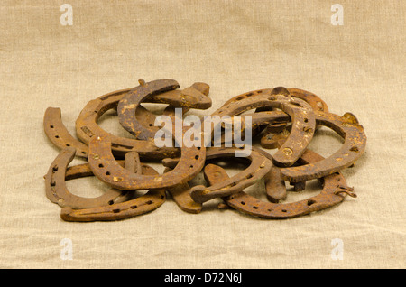 Pile de vieux rétro rusty fers isolé sur fond tissu tissu en lin. Banque D'Images